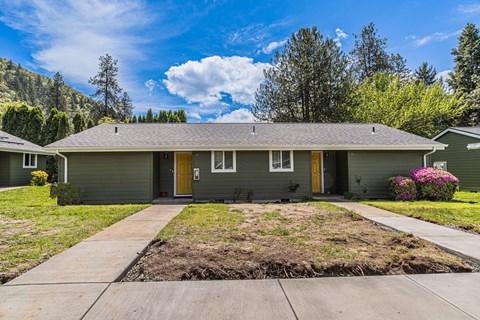 a green house with yellow doors and a sidewalk