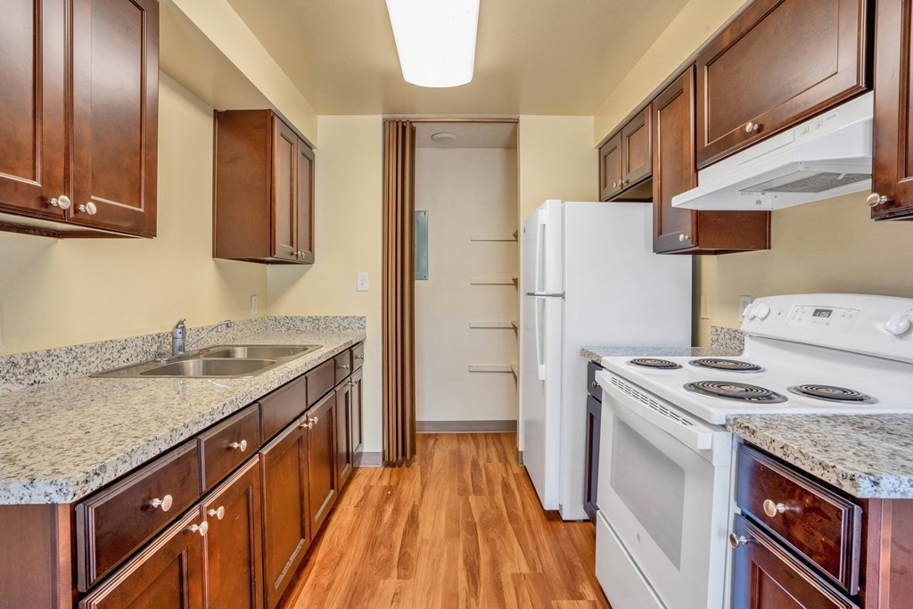 a kitchen with white appliances and wooden cabinets and granite counter tops