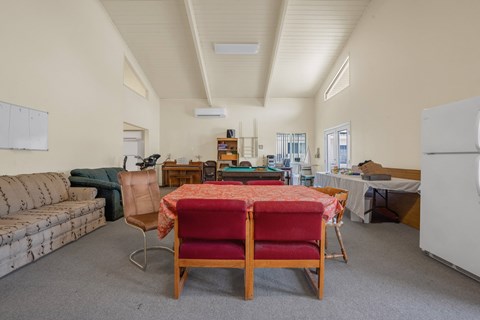 a living room with a table and chairs and a refrigerator