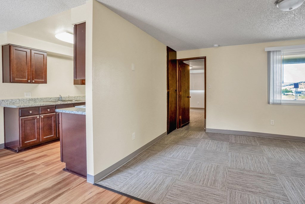 the living room and kitchen of an empty home with wood flooring