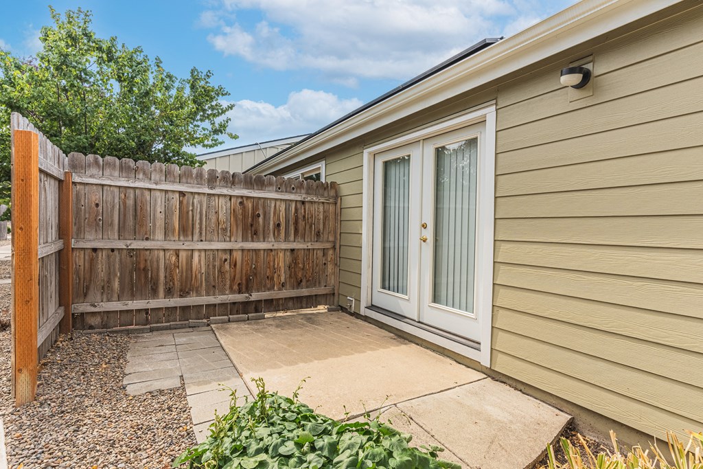 the backyard of a home with a wooden fence and a patio