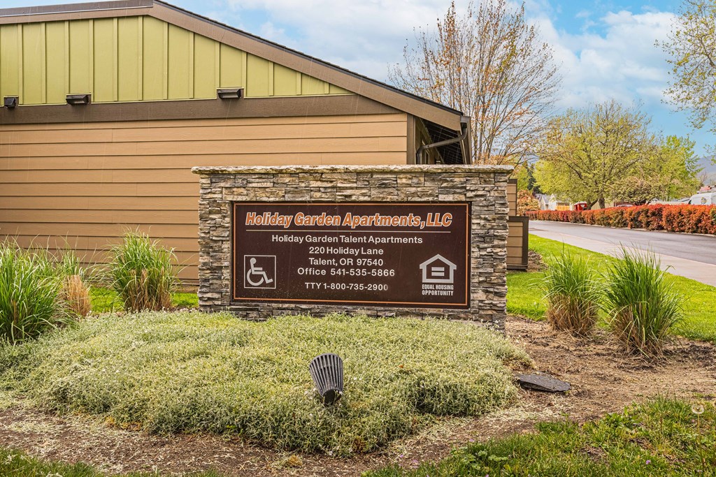 A sign for Holiday Garden Apartments, LLC is displayed in front of a building.
