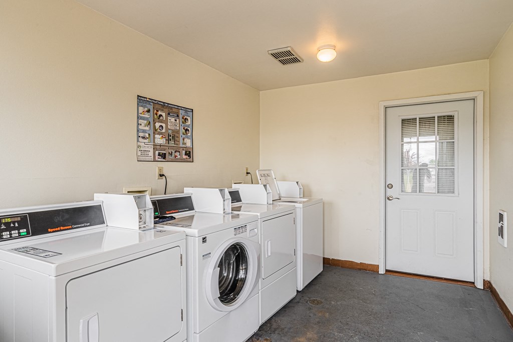 a washer and dryer room with four washing machines and a white door