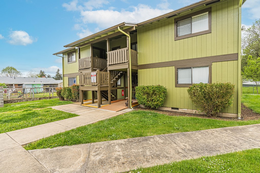 a yellow house with a balcony and a sidewalk