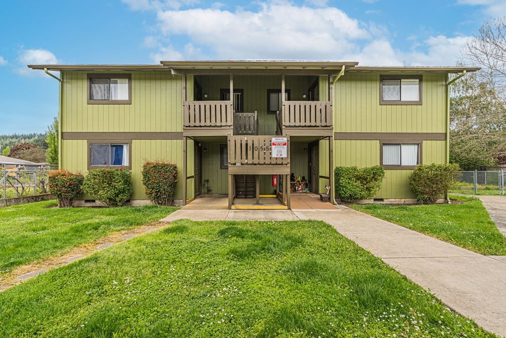 a yellow house with a porch and a sign on the front of it