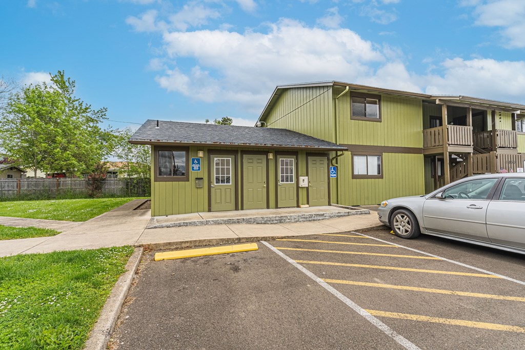 a green house with a parking lot and a car