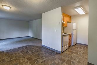 an empty living room with a refrigerator and a sink