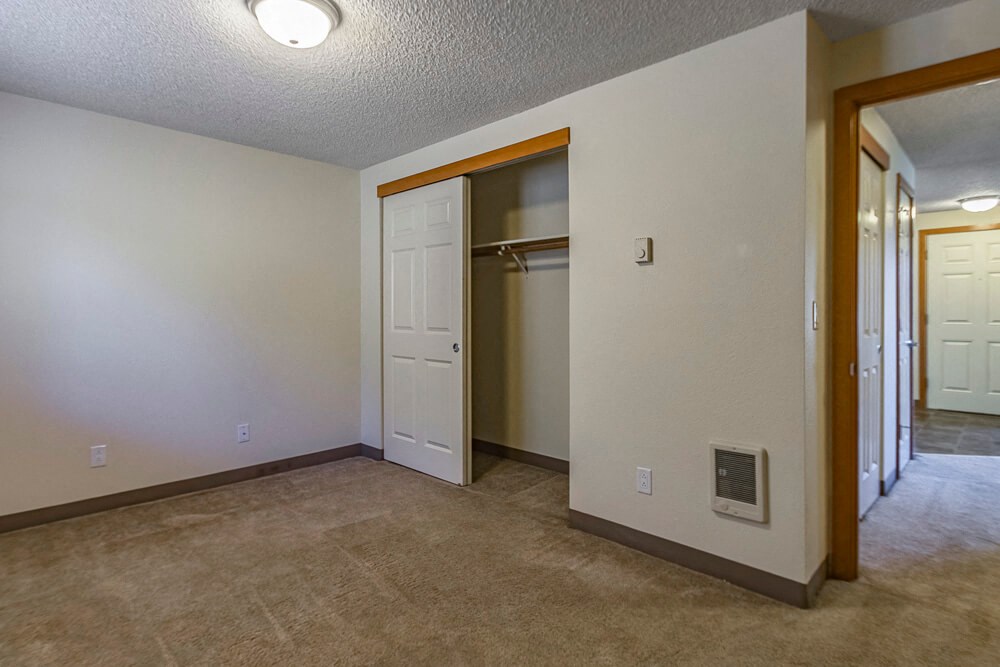 an empty living room with a door to a closet