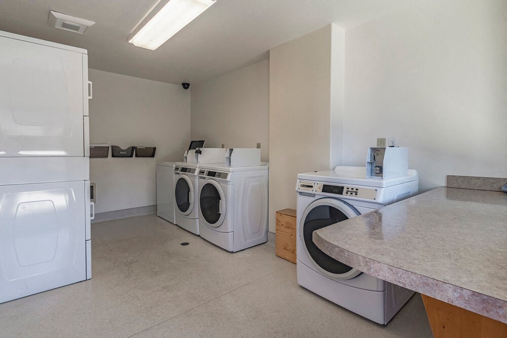 a laundry room with washes and dryers and a counter top with a sink
