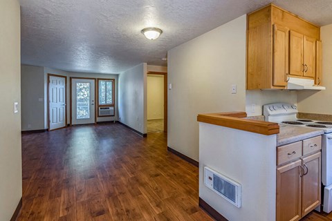 an empty kitchen and living room with wood flooring