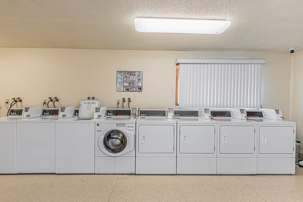 a row of white washers and dryers in a laundromat