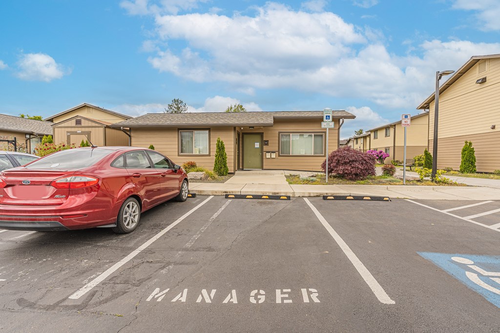 a red car parked in a parking lot in front of a building