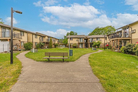 a park with a bench in front of some apartment buildings