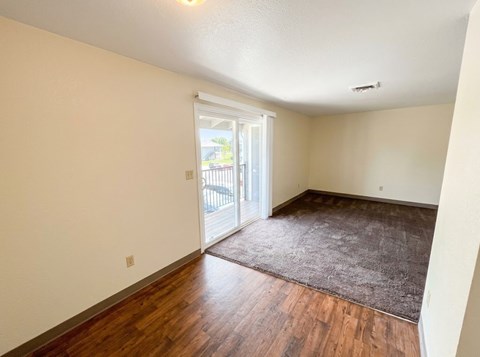 A room with a brown rug and wooden floors.
