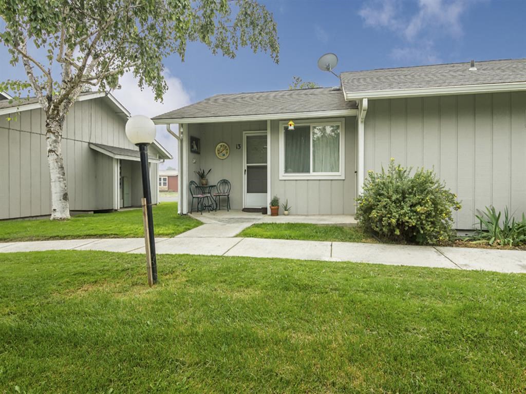 the front of a gray house with a sidewalk and lawn