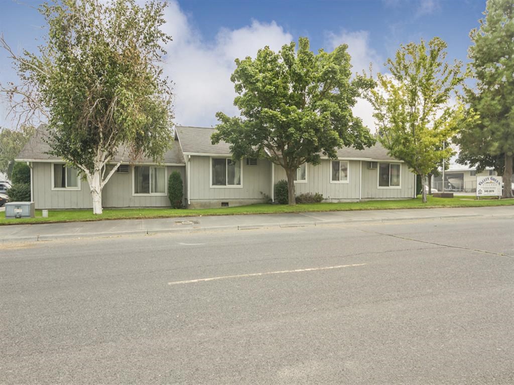 a house on the corner of a street with trees