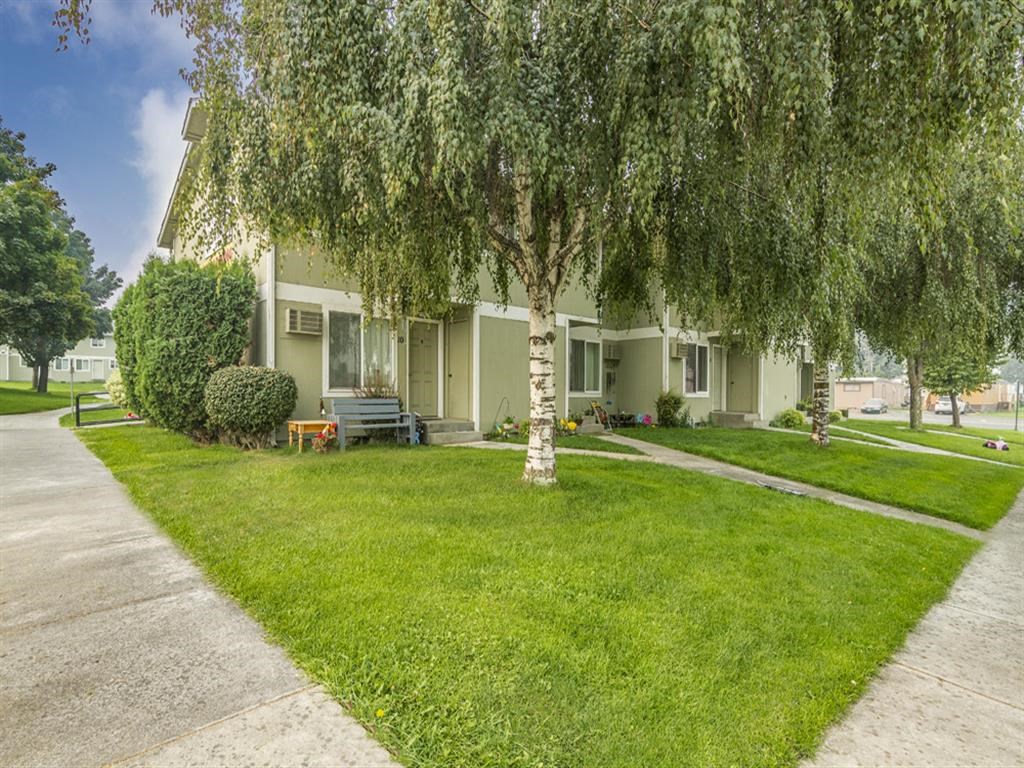 a house with trees in front of it and a sidewalk