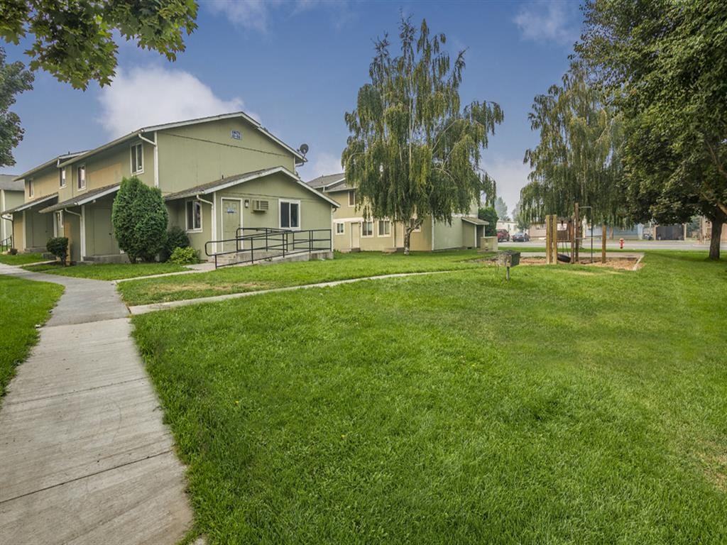 a row of houses with a sidewalk and green grass
