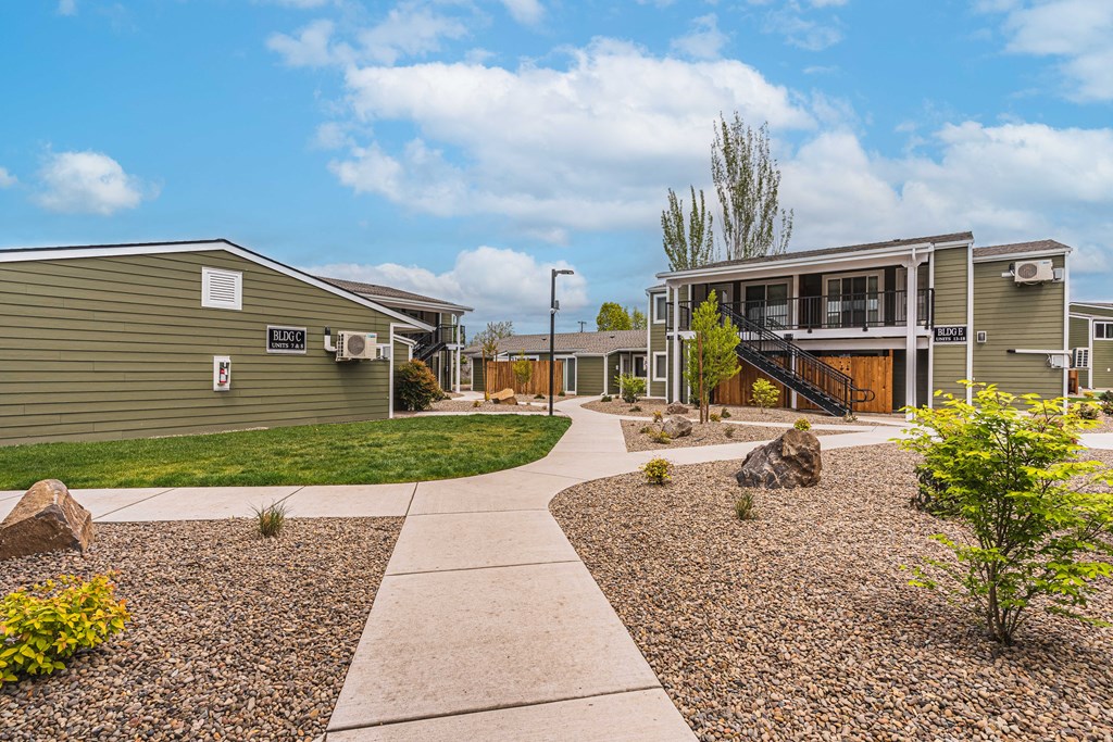 A residential area with a gravel pathway and a few trees.