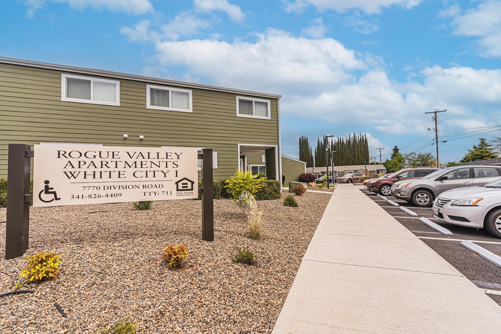 A sign for Rogue Valley Apartments in White City stands in front of a building.