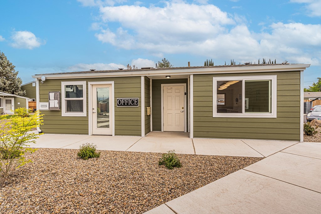 A small green house with a sign that says "OFFICE" on the front door.