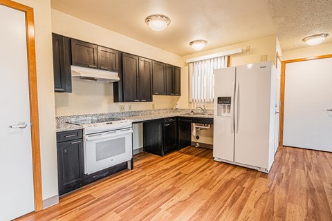 A kitchen with black cabinets and white appliances.