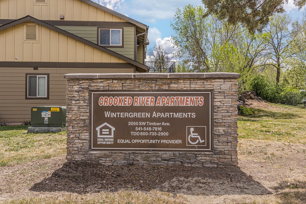 A sign for the Wintergreen Apartments stands in front of a building.