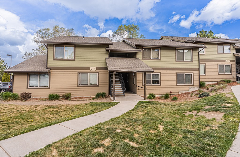 A two-story residential building with a front yard.