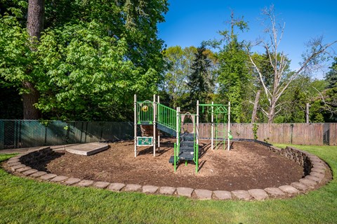 A playground with a green swing set and a sign that says "Kids Play Area".