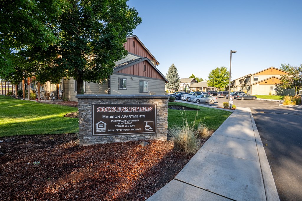 A sign for Grovewood River Apartments sits in front of a building.