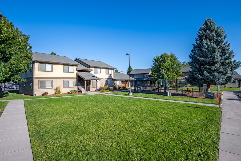 A row of houses with a green lawn in front.