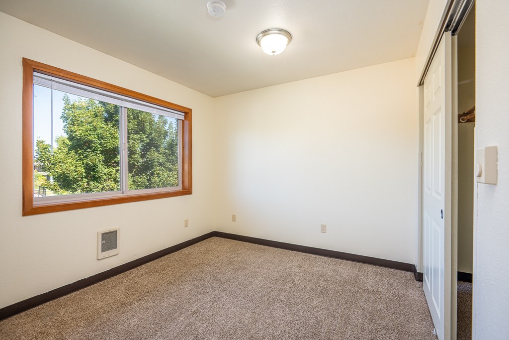 A room with a window and carpeted floor.