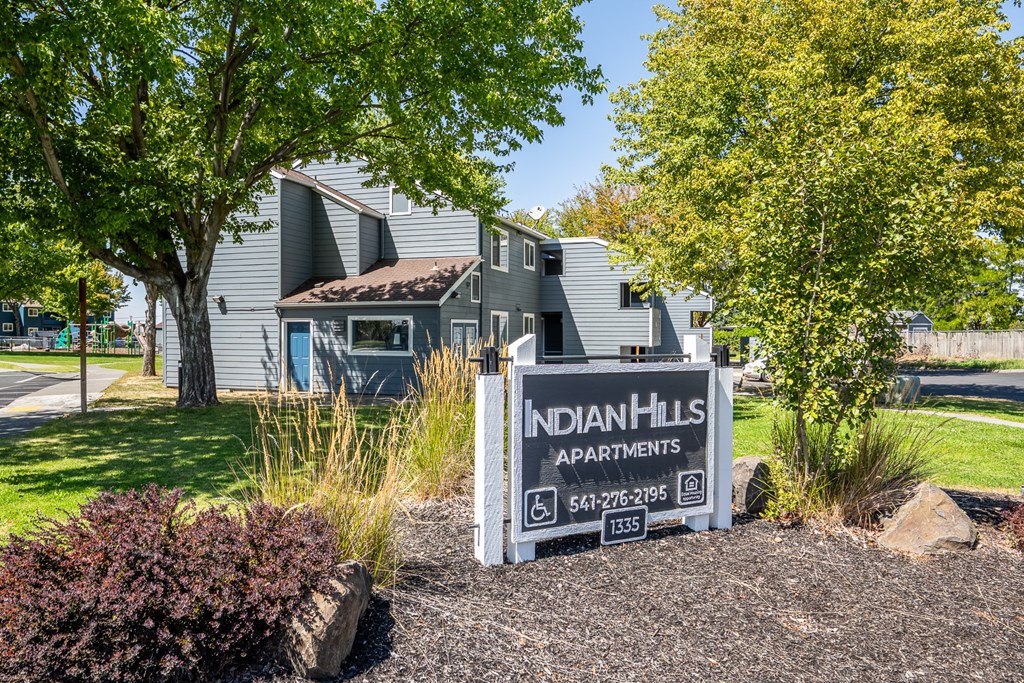 A sign for Indian Hills Apartments is in front of a building.