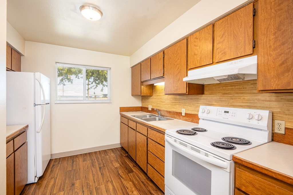A kitchen with wooden cabinets and a white stove top oven.