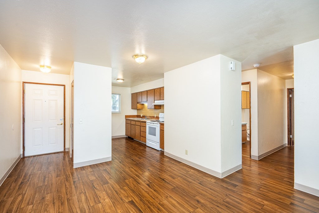 A kitchen with white walls and wooden floors.