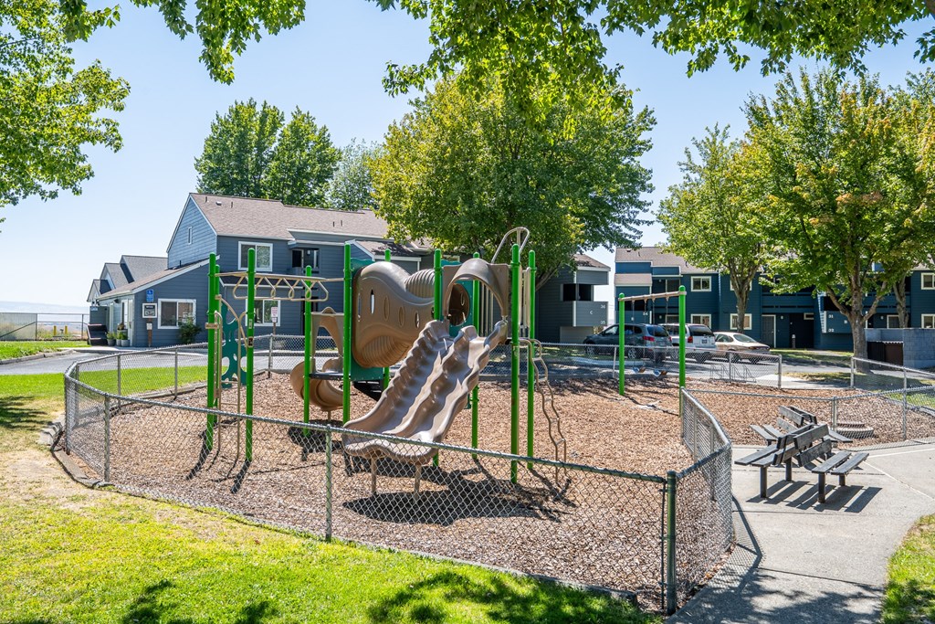 A playground with a slide, swings, and a picnic table.
