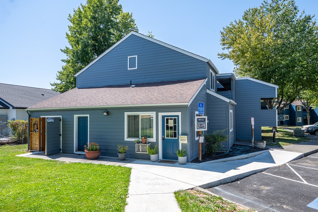 A small blue building with a white sign in front of it.