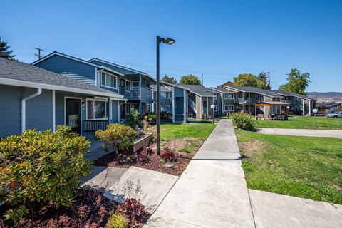 A row of houses with a sidewalk in front.