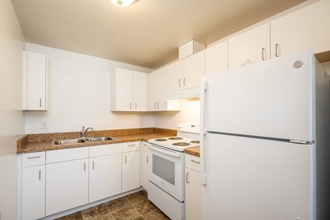 A kitchen with white appliances and cabinets.