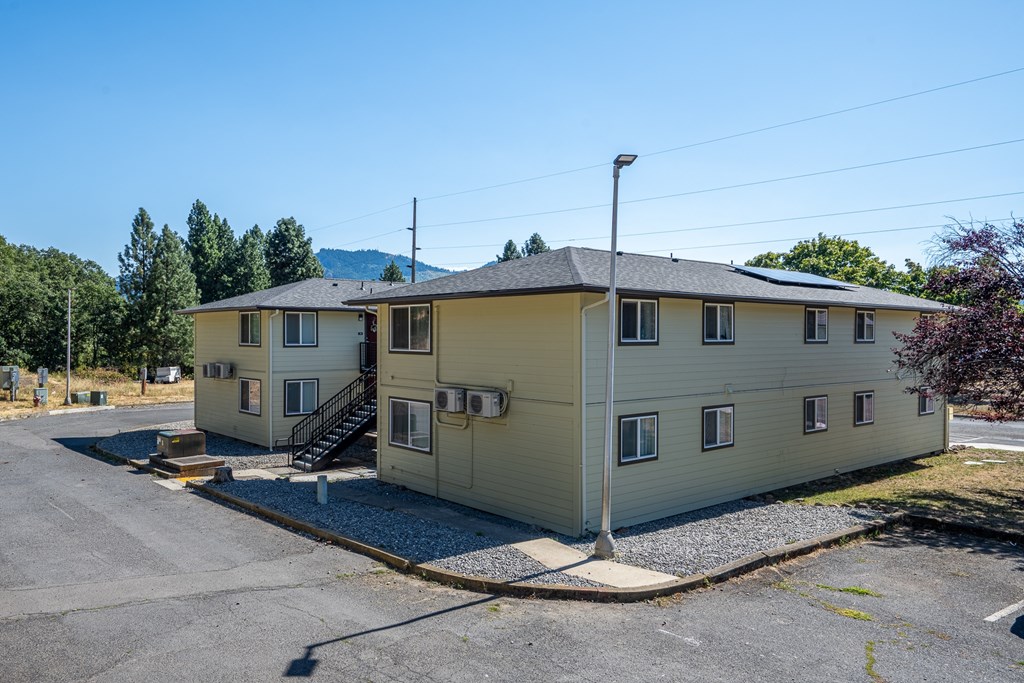 A two-story house with a gravel driveway in front.