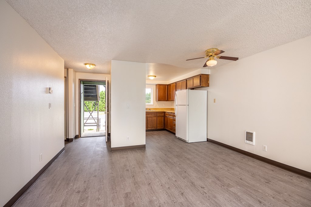 the living room and kitchen of an empty house with a ceiling fan