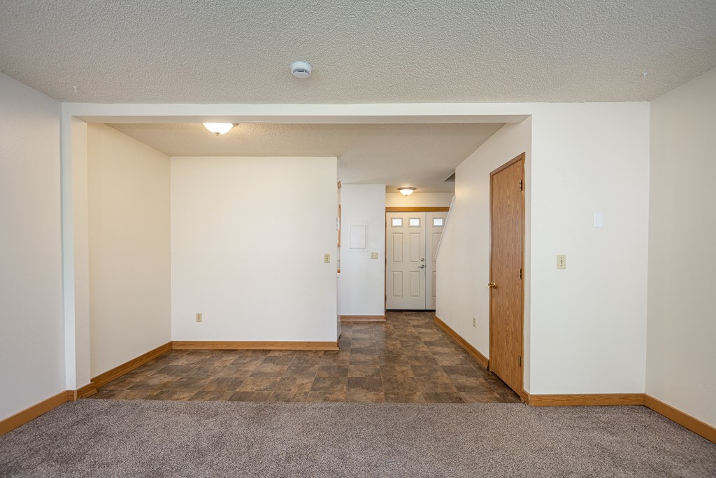 A room with a carpeted floor and a door on the right side.