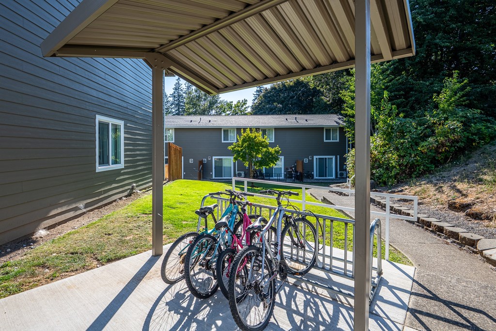 A bicycle is parked under a covered area.