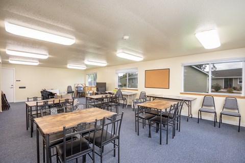 an empty classroom with tables and chairs and a chalkboard on the wall