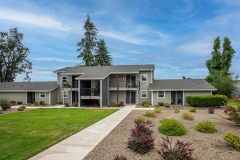 the view of an apartment building with a yard and a sidewalk