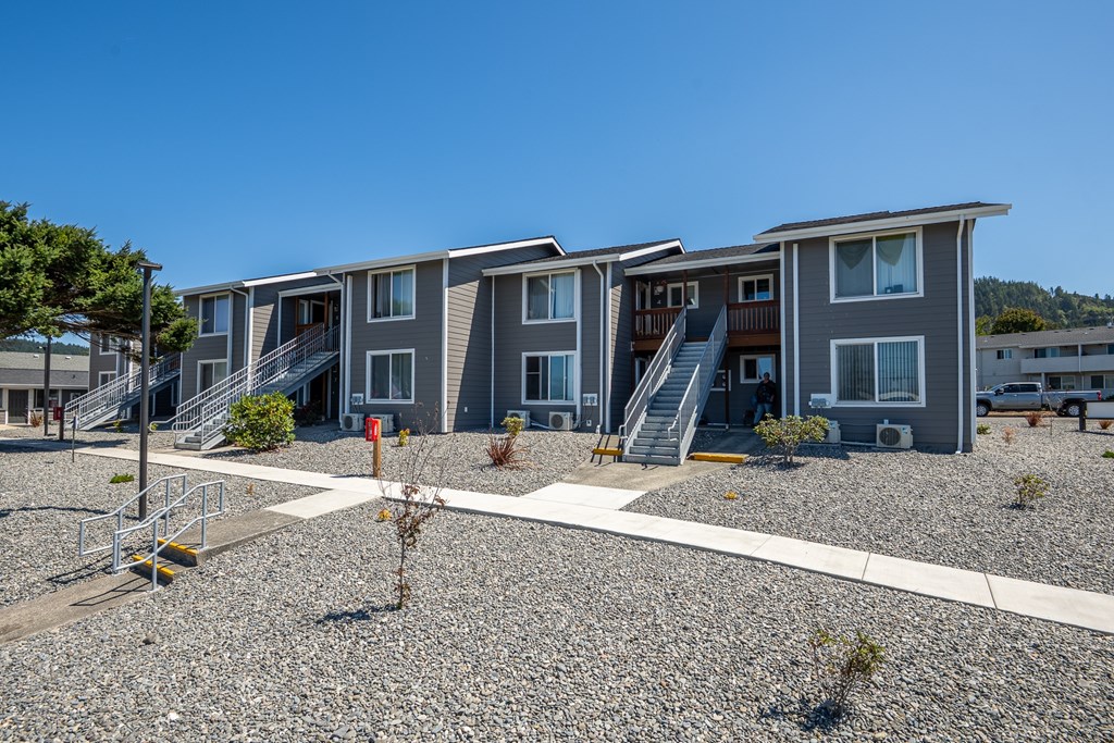 A row of modern townhouses with gravel driveways in front.