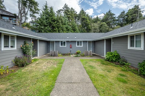 A grey house with a red fire hydrant in front.