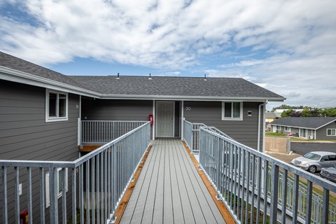 A grey house with a wooden deck and a metal railing.