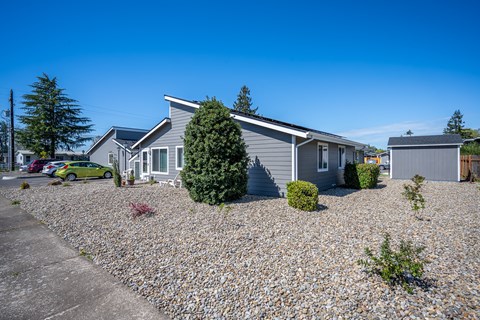 A house with a grey roof and a green car parked in front.