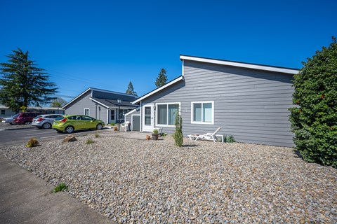 A grey house with a gravel driveway in front.